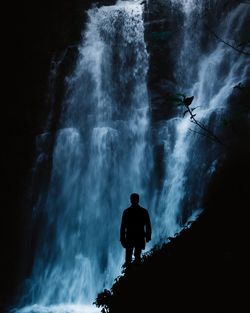 Silhouette man standing against waterfall