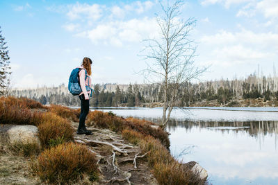 Girl traveler is resting on the shore of the lake in the spring forest. the girl enjoys nature