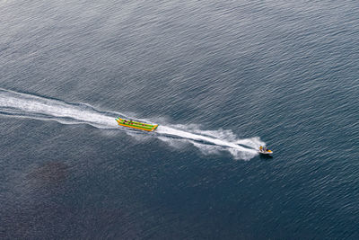 Jet ski towing on the sea inflatable banana. view from above. beautiful ripples in the sea water