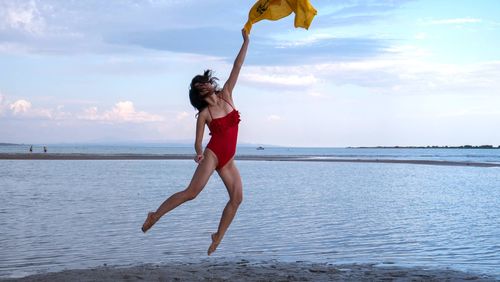 Woman standing at beach against sky