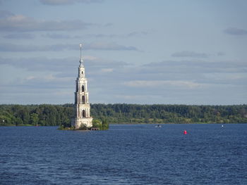 Lighthouse by sea against sky