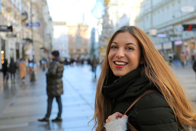 Portrait of smiling woman standing in city during winter