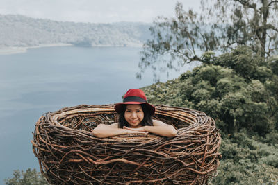 Portrait of young woman in hat against trees