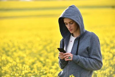 Young woman using mobile phone on field