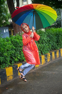 Woman with umbrella standing on wet road during rainy season