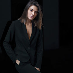 Portrait of young businesswoman standing against black background