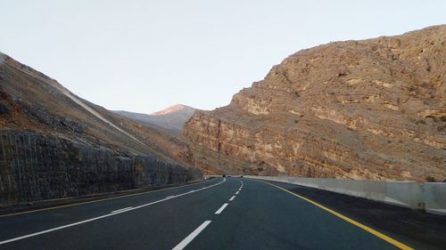 Road by mountains against sky