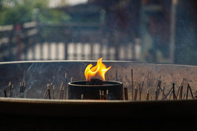 Close-up of burning candle on glass window