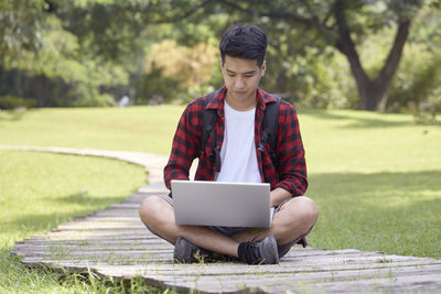 Full length of teenage girl using mobile phone in grass