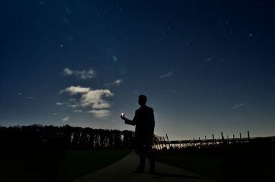 Silhouette man standing on field against sky at night