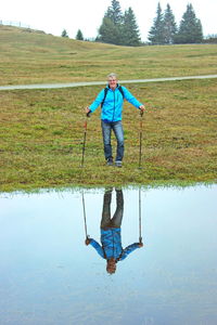Man holding umbrella standing by lake