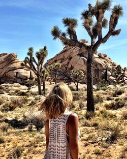 Rear view of woman walking against joshua tree on sunny day