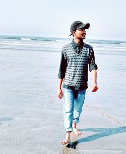 Young man standing on beach against sky