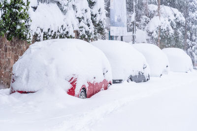 View of city street covered in snow during heavy snowfall with trapped vehicles. 