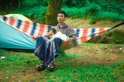 Portrait of cute daughter with father in hammock on land