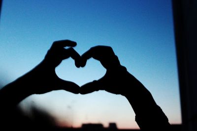 Close-up of hands holding hands against clear blue sky