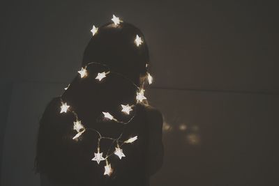 Rear view of woman with illuminated string lights