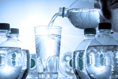 Close-up of bottle pouring water in glass on table