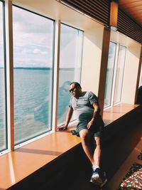 Full length of young man standing against window