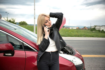 Full length of woman using mobile phone on road