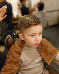 High angle view of boy looking away while sitting in hair salon