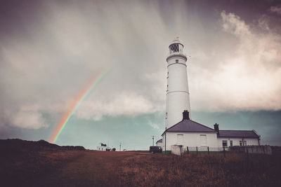 Low angle view of rainbow over buildings against sky