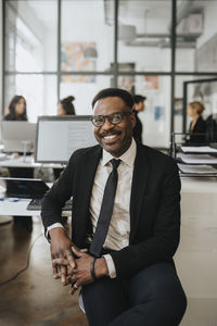 Portrait of happy male entrepreneur sitting at office