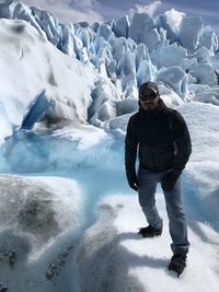 Full length portrait of young man standing in snow