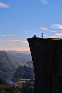 People on cliff against sky