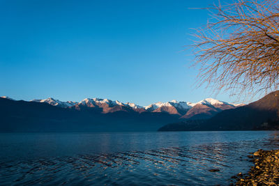 Scenic view of lake and mountains against clear blue sky