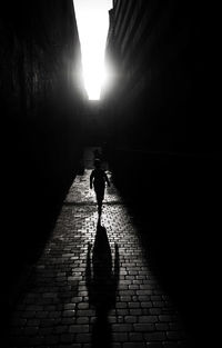 Rear view of woman walking on footpath amidst street