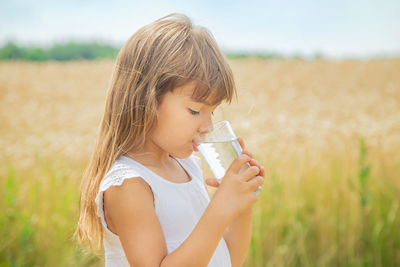 Smiling girl drinking water on field