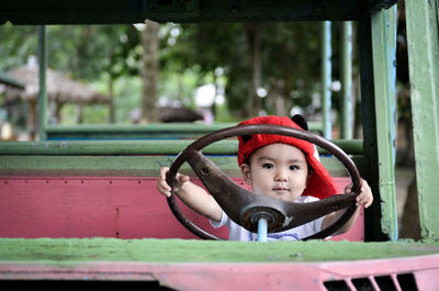 Portrait of cute boy holding steering wheel of toy car