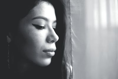 Close-up of woman by curtain