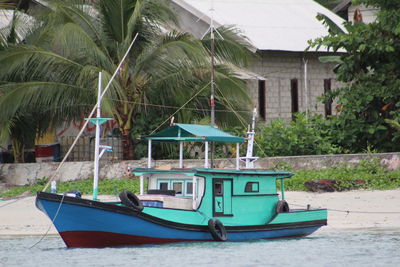 Boat moored by palm trees and building