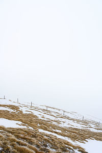 Snow covered land against clear sky