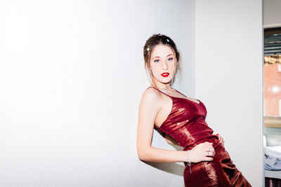 Portrait of young woman standing against white background