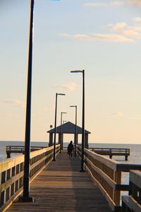 Rear view of man on pier over sea against sky