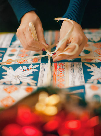 Cropped hands of woman tying gift box