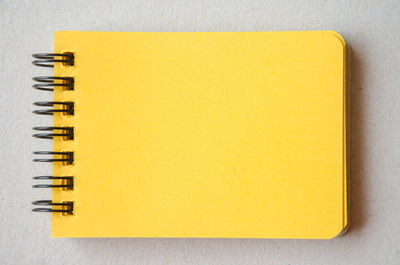 Directly above shot of yellow spiral notebook on table