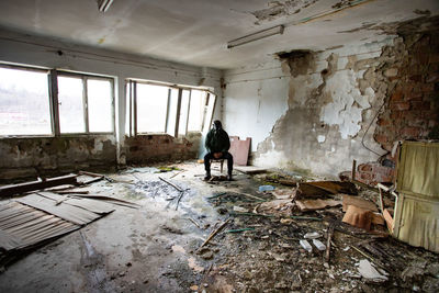 Full length of man sitting in abandoned building