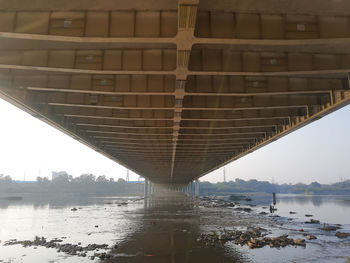 Bridge over river in city against sky