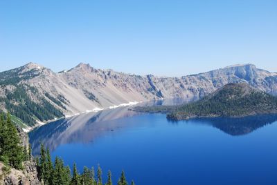 Scenic view of lake and mountains against clear blue sky