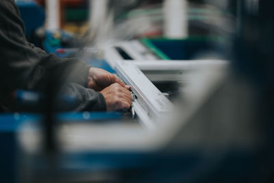 Cropped hand of manual worker making window frame at factory