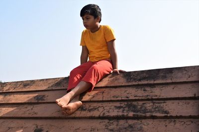 Low angle view of boy looking at camera against sky