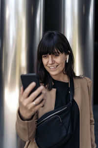 Portrait of a smiling young woman using mobile phone