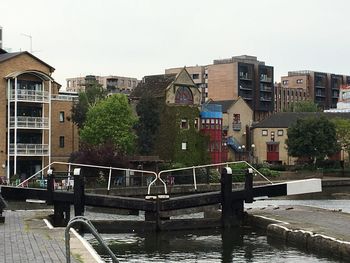 Bridge over river amidst buildings in city against clear sky