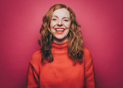 Portrait of smiling young woman against red background