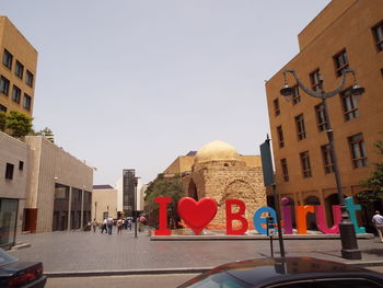 People on street amidst buildings in city against sky