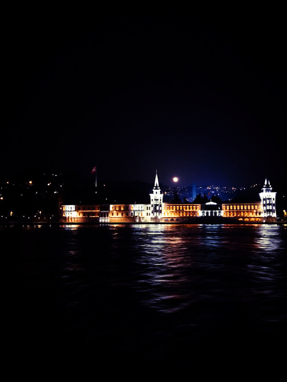 ILLUMINATED CITY BY SEA AGAINST SKY